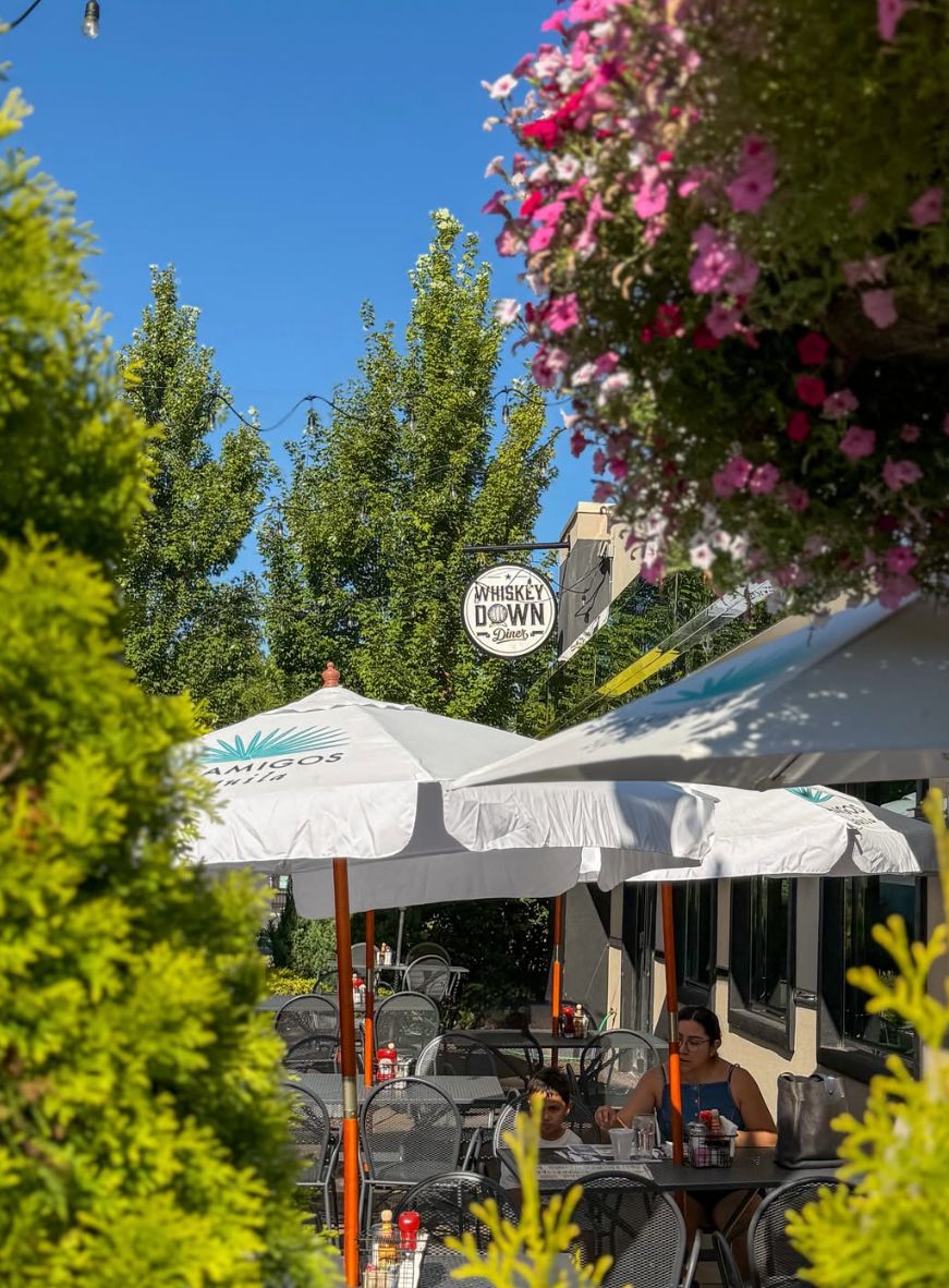 Umbrella tables on the patio in Farmingdale, with the sign above