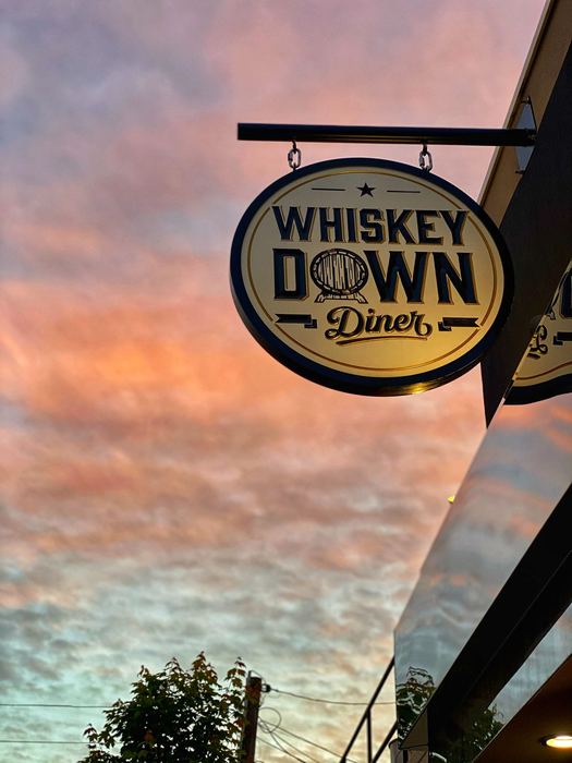 The hanging sign against a pink sunset sky
